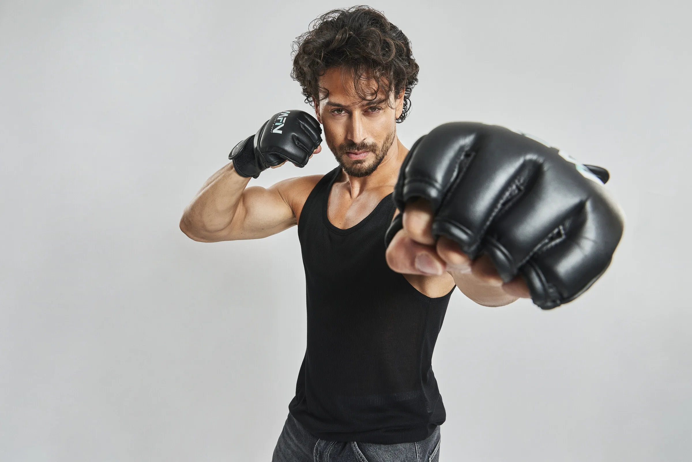 Tiger Shroff, co-founder of MMA Matrix Gym, punching towards the camera in Matrix Fight Night gloves